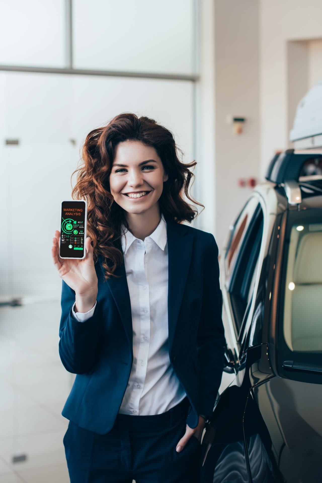 pretty businesswoman holding smartphone with graphs and charts on screen and holding hand in pocket.jpg
